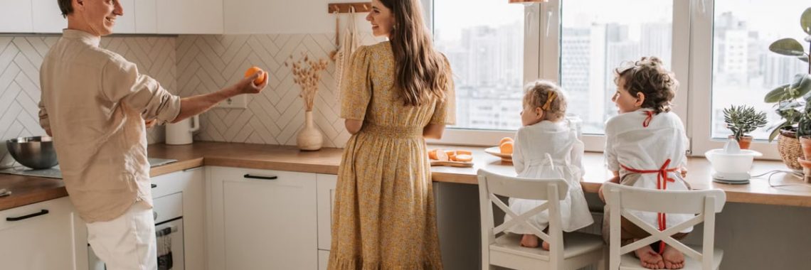 A family having fun preparing breakfast in a cozy kitchen with a city view.
