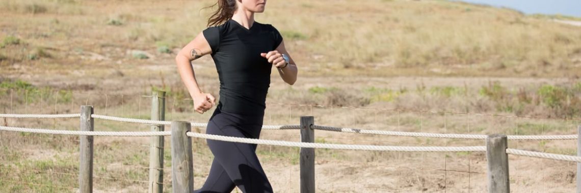 Woman jogging on a sunny day on a wooden path in Portugal, embracing a healthy lifestyle.